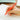 a photo of a penco orange lightweight pen in a persons hand who is writing on a notepad