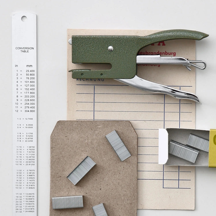 Penco Stapler on a piece of paper with a conversion table, on a light gray background.