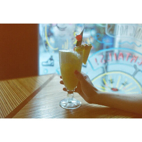 Hand holding a glass of yellow cocktail with a blurred background