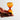 Hand holding a small 3 minute amber hourglass against a light gray background