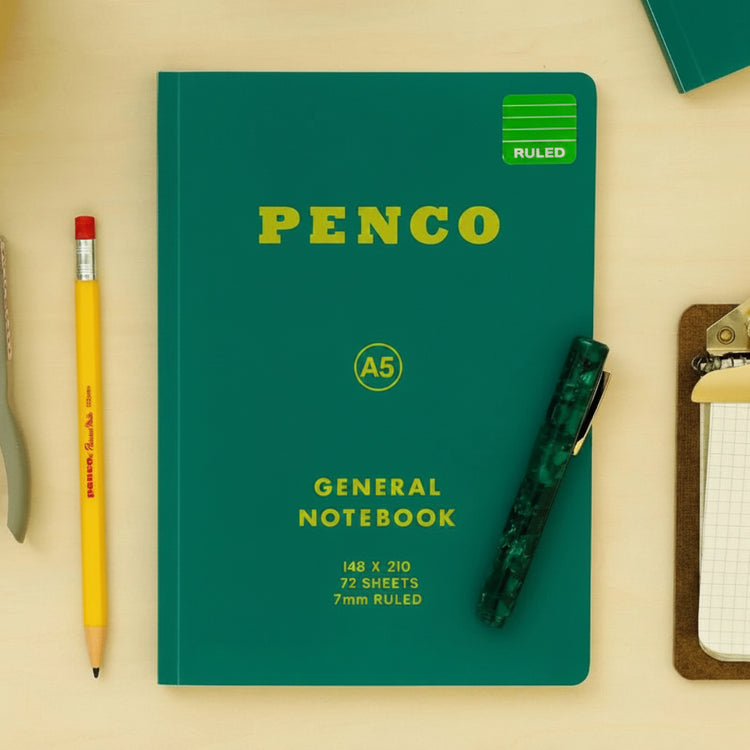 Green Penco notebook with stationery items on a beige background